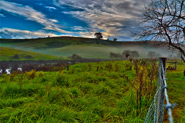 HDR photo of morning fog and green hills at sunrise on a cloudy day near Bega NSW.